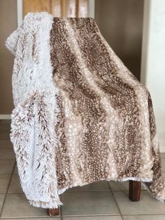 a brown and white blanket sitting on top of a wooden chair