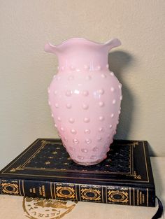 a pink vase sitting on top of a book