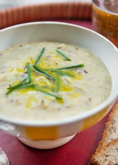 a white bowl filled with soup next to a slice of bread on a red table