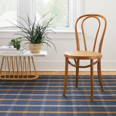 a wooden chair next to a table with a potted plant on top of it