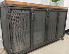 an old metal cabinet with wood top and mesh doors on wheels is sitting in front of a white wall