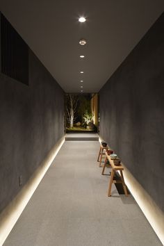 an empty hallway with benches and lights on the side wall, along with concrete walls