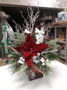 a red vase filled with white flowers and greenery