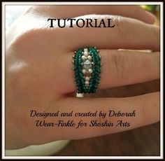 a woman's hand wearing a ring with pearls and green beadwork on it