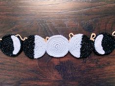 three crocheted black and white ornaments on a wooden table