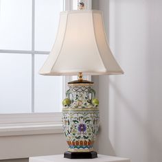 a lamp that is sitting on top of a table next to a window with white curtains