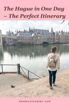 a woman walking along the edge of a body of water with buildings in the background