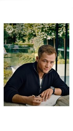 a man sitting at a table with a pen in his hand