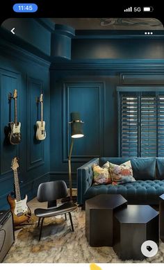 a living room filled with furniture and guitars on the wall next to a window covered in shutters