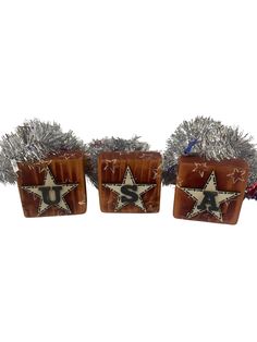 three christmas decorations with silver tinsels and stars on the top one is brown