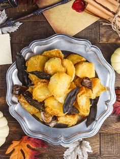 a bowl filled with fried food on top of a wooden table next to pumpkins