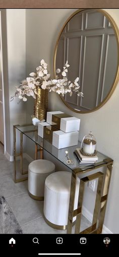 a table with a mirror, stool and vase on it