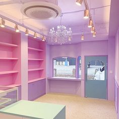 an empty room with pink and purple walls, chandelier and open shelving