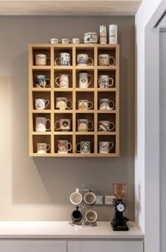 coffee mugs are arranged on wooden shelves in the corner of a room with white walls