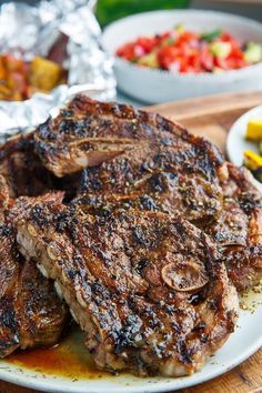 some meat is sitting on a plate next to other foods and condiments in bowls