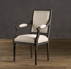 an antique chair with white upholstered fabric and wood legs on a wooden floor