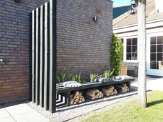 a bench sitting in front of a brick wall next to a tree and planter