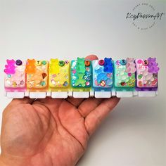 a hand holding a row of colorful bear erasers on top of each other in front of a white background