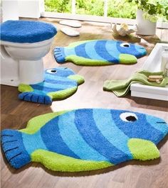 two blue and green fish rugs sitting on top of a wooden floor next to a toilet