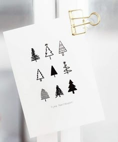 a piece of paper with christmas trees drawn on it hanging from a clipping in front of a door