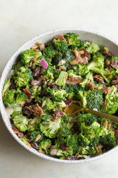 a white bowl filled with broccoli and other food on top of a table