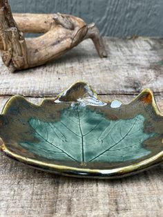 a leaf shaped bowl sitting on top of a wooden table