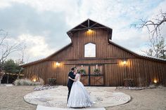 a bride and groom standing in front of a barn