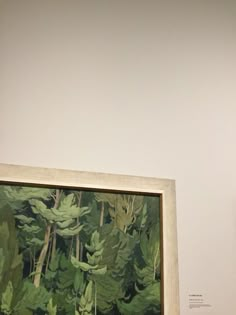 a painting hanging on the wall next to a vase with flowers and leaves in it