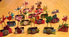 an assortment of colorful paper owl decorations on wooden sticks with bows and tags attached to them