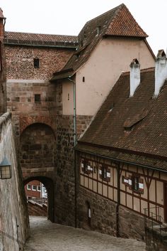 an alley way between two buildings with brick walls and arched doorways on either side