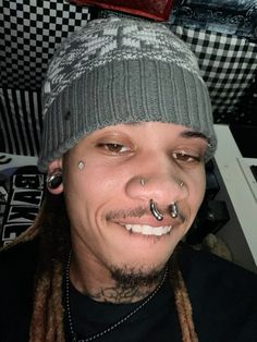 a man with piercings on his nose wearing a hat