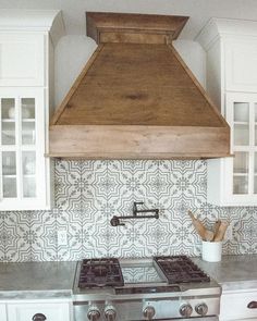 a stove top oven sitting inside of a kitchen next to white cupboards and cabinets