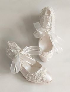 two pairs of white shoes with bows and laces on them, one is for the bride