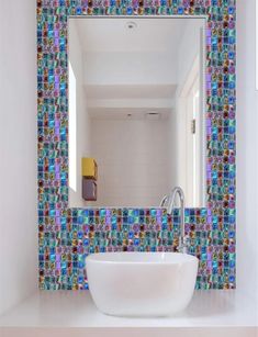 a bathroom sink sitting under a mirror next to a tiled wall