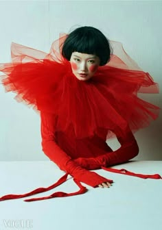 a woman with black hair wearing a red dress and holding her hands on her hips