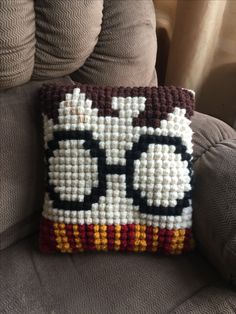 a pillow made to look like an owl with glasses on it's face, sitting on a couch