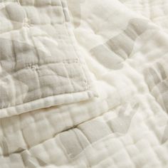 an unmade quilted bed spread with white and black designs on it's edges