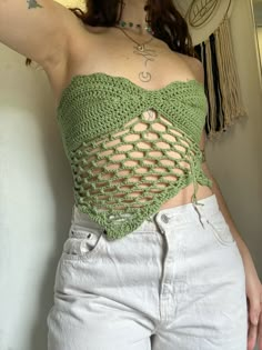 a woman wearing white jeans and a green crochet top