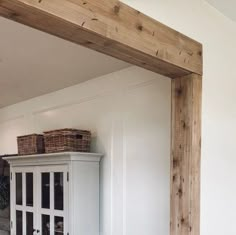 an empty room with white walls and wooden beams on the wall, including a cabinet