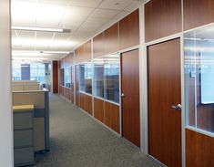 an office cubicle with wooden doors and glass partitions on the walls, along with two computer desks