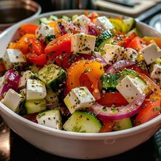 a white bowl filled with assorted veggies and feta cheese on top