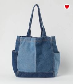 a denim tote bag with two pockets and a heart on the front, against a white background