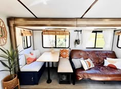 a living area with couches, tables and windows in a trailer home that has been converted into a mobile home