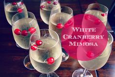 white cranberry mimosa in wine glasses with cherries on the rim