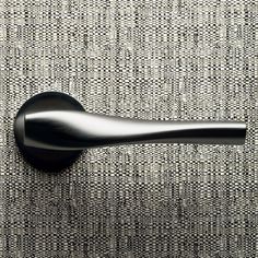 a black door handle on the side of a gray fabric wallpapered room with vertical stripes