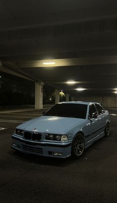 a blue car parked in a parking lot next to a light at the end of it's tunnel