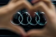 someone is holding their hands up to show the front end of an audi car logo