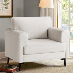 a white chair sitting on top of a rug in a living room next to a window