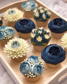 cupcakes decorated with blue frosting and flowers on a wooden platter, ready to be eaten