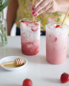 two glasses filled with ice and strawberries sitting on a table next to each other